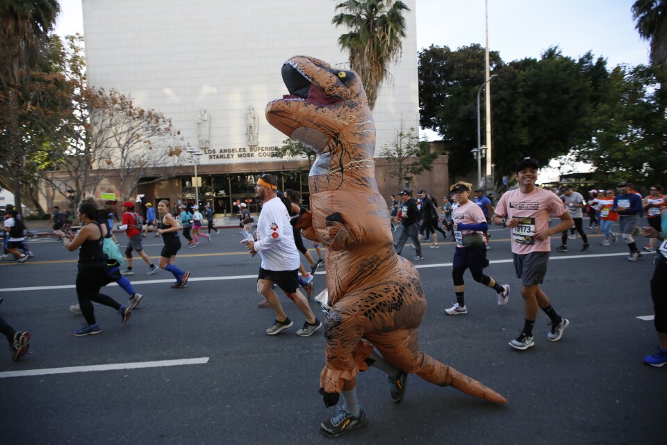 A marathon runner dressed as a T. Rex Dinosaur competes in the Los Angeles Marathon downtown Los Angeles Sunday, March 18, 2018. 