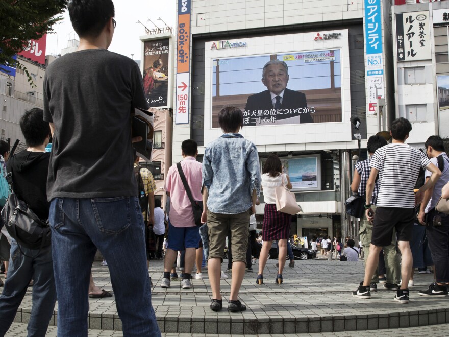 Pedestrians in Tokyo watch as Emperor Akihito speaks to the nation. In the rare video message, Akihito said old age and illness may make it difficult for him to fulfill his public duties.