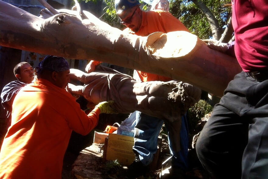Workers remove a damaged statue of Jesus from the San Gabriel Mission Cemetery crucifix memorial.