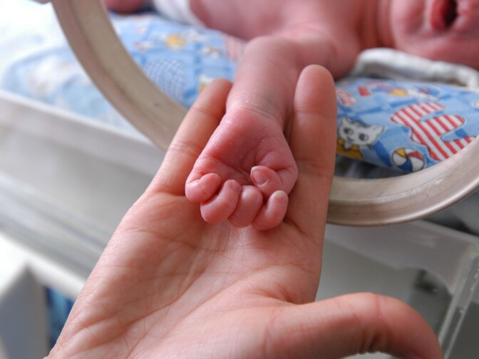 A parent holds the hand of their newborn child