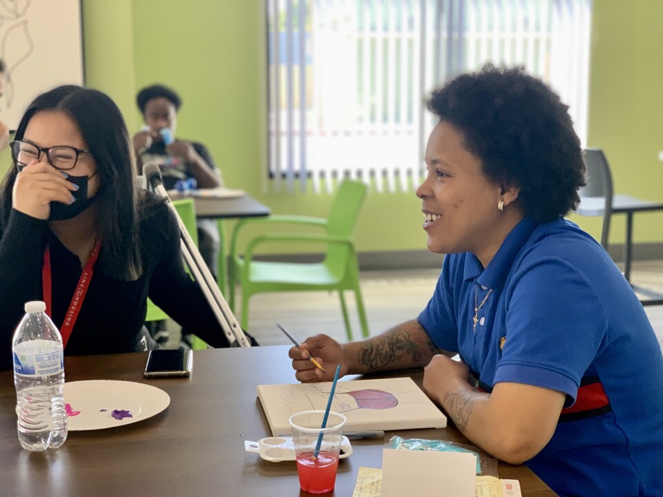 Two people sit together inside at a table.