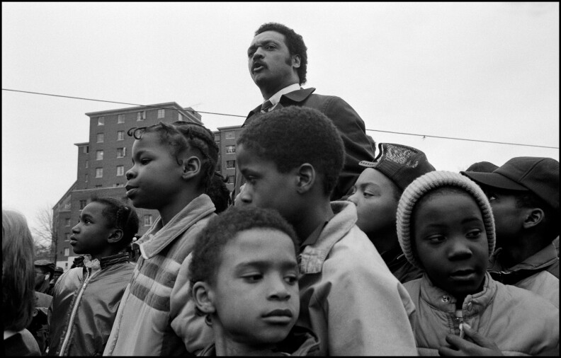 Jesse Jackson stands surrounded by children.