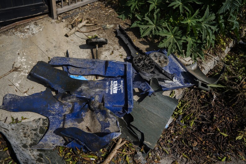 A blue plastic trash can is demolished on the ground.