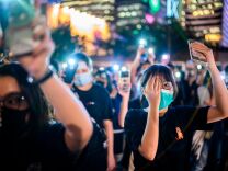 TOPSHOT - Secondary school students cover their right eye as they hold up their phone torches while attending a rally at Edinburgh Place in Hong Kong on August 22, 2019. - Hong Kong student leaders on Thursday announced a two-week boycott of lectures from the upcoming start of term, as they seek to keep protesters on the streets and pressure on the government. (Photo by Anthony WALLACE / AFP)        (Photo credit should read ANTHONY WALLACE/AFP/Getty Images)