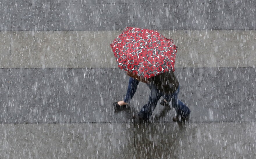 File: An umbrella is shared as rain pelts downtown Sacramento, Calif., Friday, March 4, 2016. 