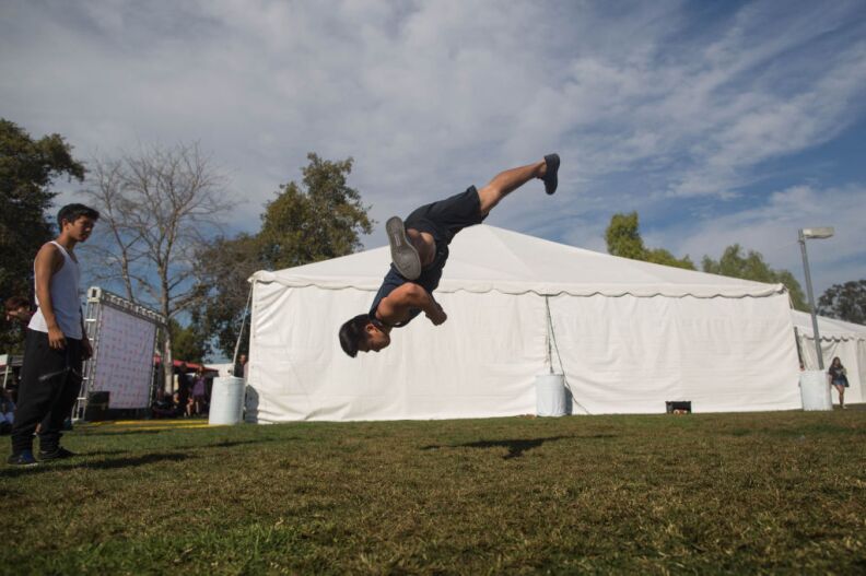 Brian Le, 19, of Westminster practices martial arts tricking in a yard behind a tent at the Verizon Ampitheatre.
