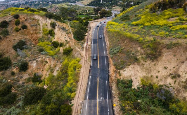 An overhead photo of a road in a hilly area that is damaged.