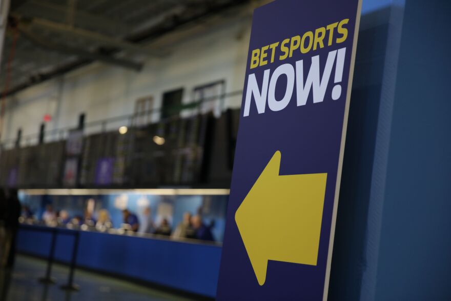 A sign reads Bet Sports Now with a yellow arrow pointing left to a counter in the background.