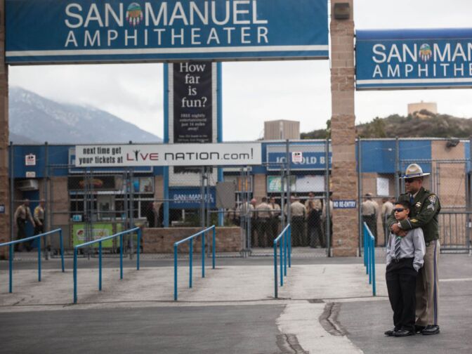 A California Highway Patrolman stands outside the funeral venue with his son on Thursday.