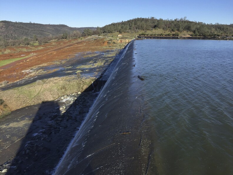 In this Feb. 11, 2017, photo released by the California Department of Water Resources, water flows over an emergency spillway at the Oroville Dam at Lake Oroville in Oroville, Calif. Water will continue to flow over the emergency spillway at the nation's tallest dam for another day or so, officials said Sunday. (Albert Madrid/California Department of Water Resources via AP)