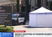 A white Newport Beach Police CSI tent is set up beyond yellow police tape in a mall parking lot. A sign for the valet and restaurants is in the foreground and a police car is parked next to the tent.