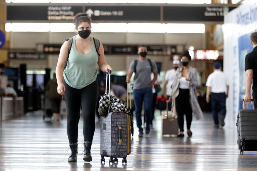 WASHINGTON, DC - MAY 25:  Travelers walk through the concourse with their luggage at Ronald Reagan Washington National Airport May 25, 2021 in Arlington, Virginia. According to AAA, more than 37 million Americans are expected to travel, either by driving, flying or catching a train, over the Memorial Day weekend this year.   (Photo by Alex Wong/Getty Images)