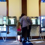 A little girl watches her mother vote on June 5, 2012 at City Hall in Hudson, Wisconsin, for current Governor Scott Walker or challenger Milwaukee Mayor Tom Barrett.
