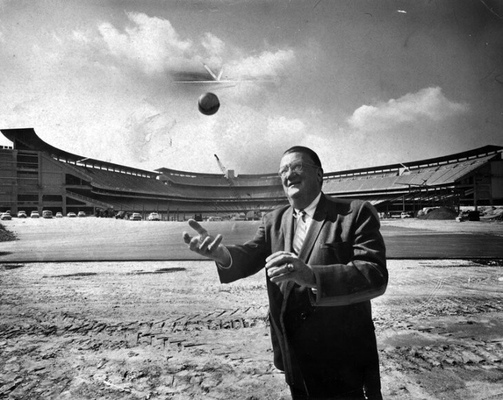 A man in a suit tosses a baseball in the air.