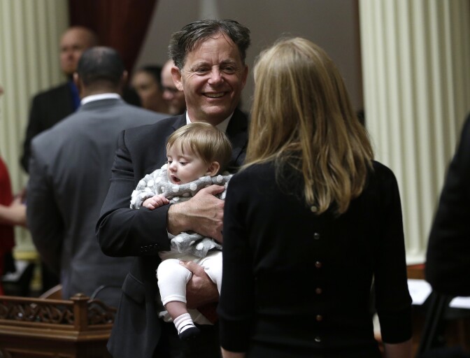 File: Freshman state Sen. Josh Newman, D-Fullerton, holds his daughter Cecily, six months, as he waits to be sworn-in to the state Senate, in Sacramento, Calif., Monday, Dec. 5, 2016. Newman was joined for the ceremony by his wife, Darcy Lewis, right.