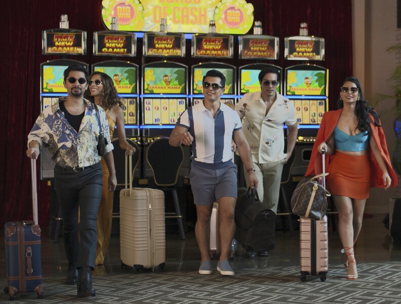 Five people walk with their bags through a casino.