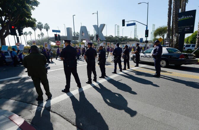 LOS ANGELES, CA - NOVEMBER 21:  Los Angeles Police department officer look on as a large march by service employees and members from several other unions on the main thoroughfare to the entrance of Los Angeles International Airport during a large protest a day before Thanksgiving on the busiest travel day of the year November 21, 2012 in Los Angeles, California.  Over a thousand protesters blocked the main street leading to LAX in protest what their union called unfair labor practices by an airport contractor. (Photo by Kevork Djansezian/Getty Images)
