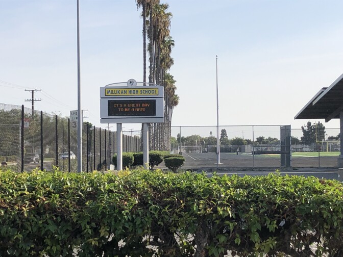 A photo of a campus sign from Millikan High School next to a parking structure.