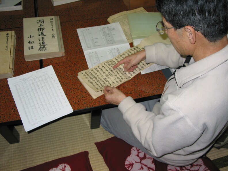 The Priest Mr. Kiyoshi Miyasaka pointing out some of the records on lake ice and the omiwatari. His data sheet summarizing the records are on the table. Taken Nov. 3, 2005.