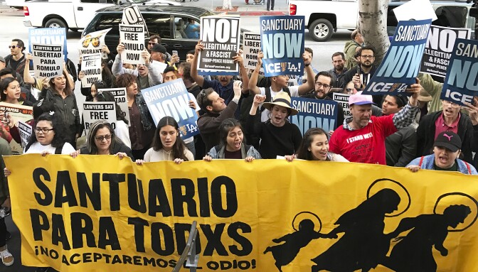 Some of about 100 people demonstrate outside a federal immigration court in Los Angeles on Monday, March 6, 2017, protesting the arrest of an immigrant who has been ordered deported. Romulo Avelica-Gonzalez was arrested Feb. 28, 2017, after dropping his daughter off at school in Los Angeles. (AP Photo/Michael Balsamo)