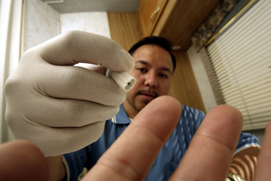 A mobile testing program manager uses a photographer's finger to demonstrate how to obtain a blood sample to test for HIV inside a mobile HIV screening lab in Los Angeles, California.