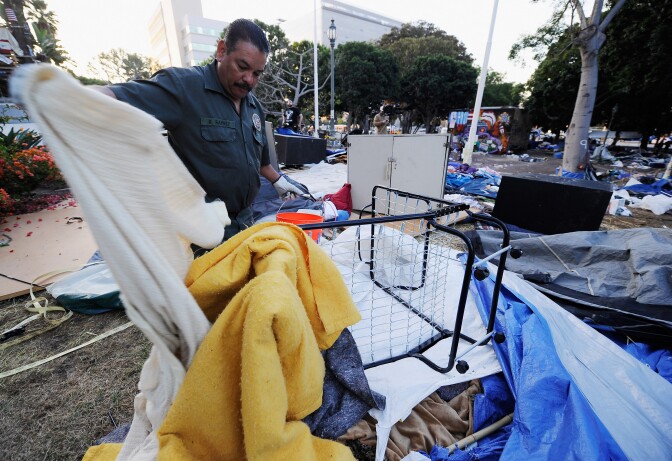 LOS ANGELES, CA - NOVEMBER 30:  Gino Ramirez, from Los Angeles Sanitation Department, picks up blankets during cleanup of the Occupy Los Angeles encampment following the Los Angeles Police Department raid on November 30, 2011 in Los Angeles, California. Protesters remained on the City Hall lawn despite a deadline, set by Los Angeles Mayor Antonio Villaraigosa, to dismantle their campsite and leave the park which the city declared closed as of 12:01 am November 28th.  (Photo by Kevork Djansezian/Getty Images)