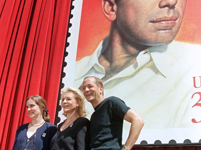 Actress Lauren Bacall (C) and her two children Stephen (R) and Leslie (L) by former husband Humphrey Bogart pose in front of a stamp commemorating his life July 31, 1997 during a stamp unveiling ceremony in Hollywood. The stamp portrait is from the movie poster for the 1946 film "The Big Sleep."
