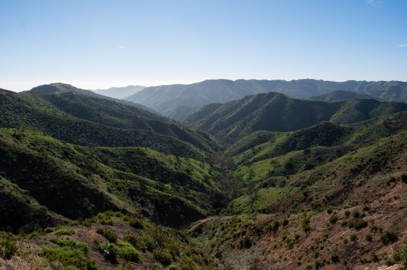 A mountain range that's green under a blue sky.