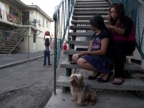 Claudia Chi Ku braids the hair of her daughter, Leslie Soriano, 11, as her other children play outside of their apartment in Pico Union. Chi Ku supports her family while working as a cashier at a restaurant in the neighborhood.