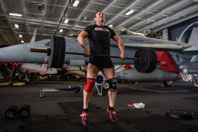 (March. 2, 2018) Lt. Joshua Johnson lifts weights in the hangar bay of the aircraft carrier USS Theodore Roosevelt (CVN 71).