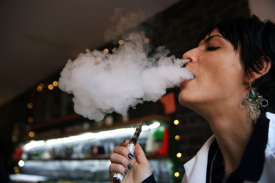 Catharine Candelario, an employee at the newly opened Henley Vaporium, vapes, or smokes an electronic cigarette, on December 19, 2013 in New York City. 