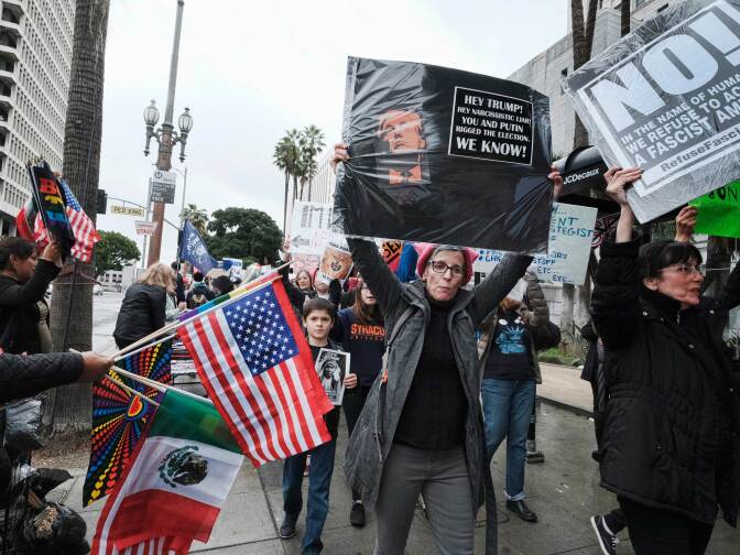 Protesters march down a street past Los Angeles City Hall on Monday, Feb. 20, 2017. Demonstrators gathered to express their opposition to President Donald Trump and take part in a "Not My President's Day" rally.