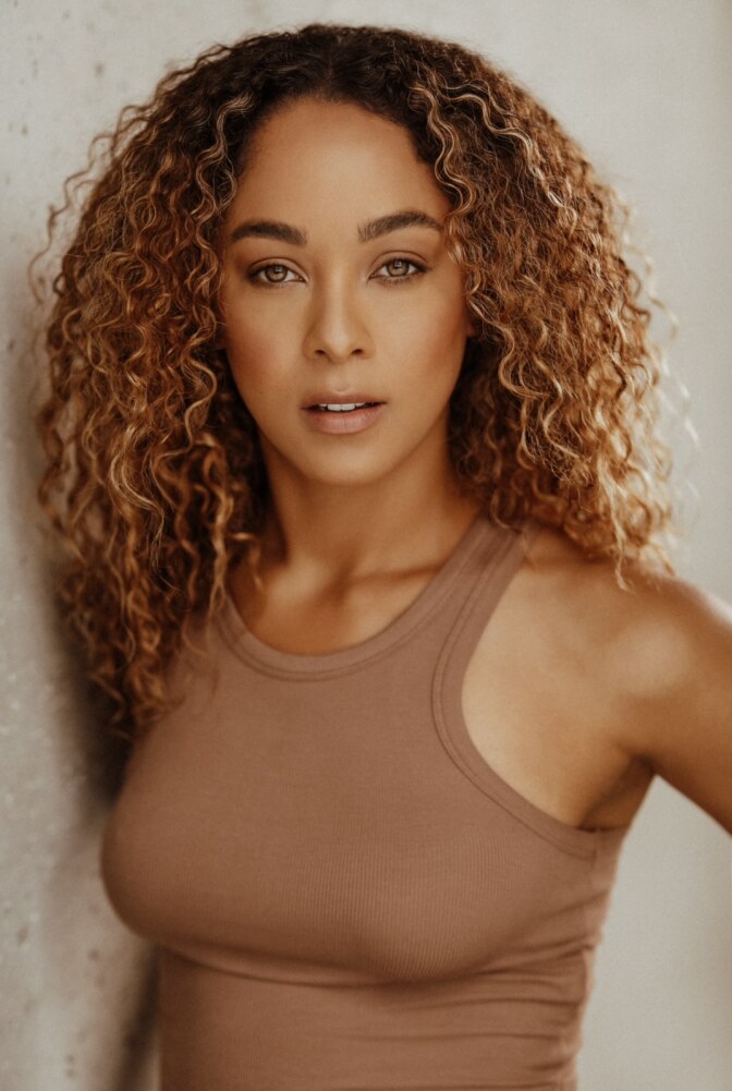 A woman with medium-tone skin and long dark curly hair.