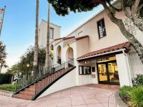 A Spanish-style building has a tiled exterior staircase and a sign above a first floor entrance that reads: San Gabriel City Hall