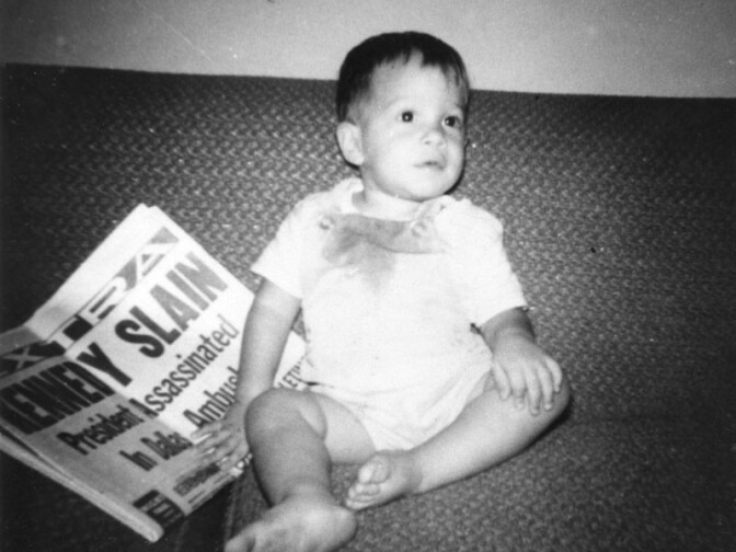 1963: Baby Daniel Rodriguez with newspaper that has President Kennedy assasination headline. 