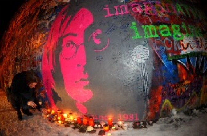 A young woman lights a candle in front of John Lennon's wall memorial to commemorate the 30th anniversary of the musician's death.