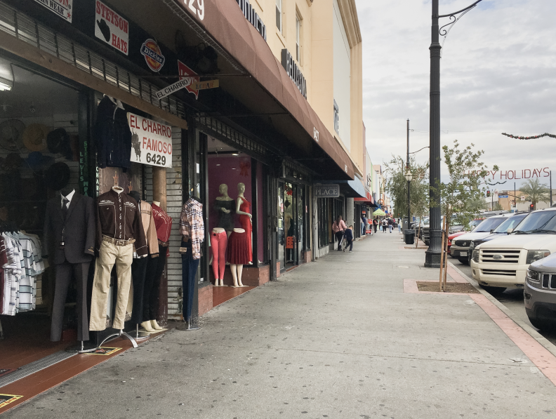 The exterior of a store selling cowboy-style wear next to a sidewalk, with cars parked alongside.