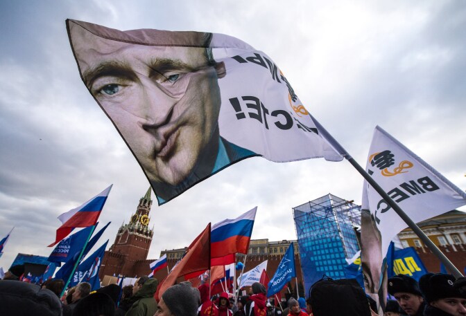 With a flag depicting President Vladimir Putin (C) pro-Kremlin activists rally at the Red Square in Moscow, on March 18, 2014, to celebrate the incorporation of Crimea. Putin pushed today every emotional button of the collective Russian psyche as he justified the incorporation of Crimea, citing everything from ancient history to Russia's demand for respect to Western double standards.