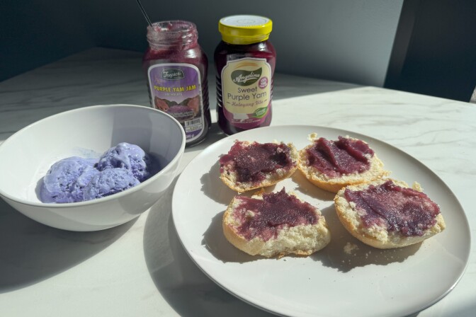  Four slices of bread spread with purple ube halaya on white plate next to ube ice cream bowl and jars.