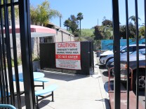 A wide view of the small triage center in the parking lot. It's fence off with a large sign that says in red and black letters, caution: emergency marine mammal triage area. Do not enter.