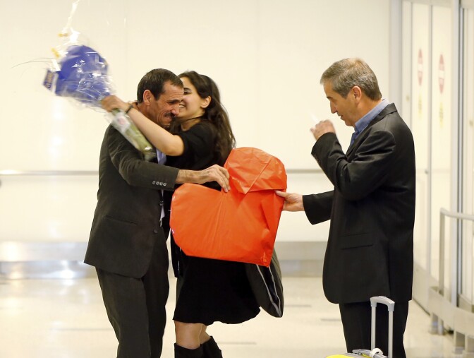 Ali Vayeghan, an Iranian citizen with a valid U.S. visa, left, is kissed by his niece Marjan Vayghan, as his brother Houssein Vayghan welcomes his as he arrives at Los Angeles International Airport Thursday, Feb. 2, 2017. An Iranian man turned away from Los Angeles International Airport under President Donald Trump's executive order barring people from seven Muslim-majority nations has arrived back in the U.S. under a federal judge's order. (AP Photo/Damian Dovarganes)