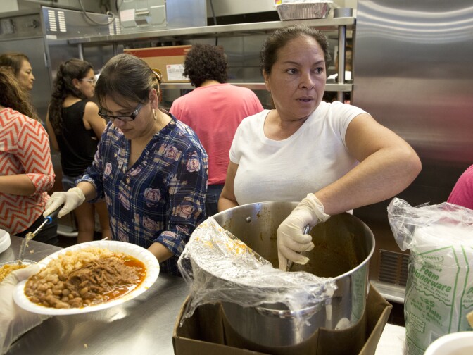 Teresa Lazcano (on left) and Geisa Aligria, volunteers for The Guadalupe Homeless Project serve up a homemade evening meal at Proyecto Pastoral on July 13, 2016.