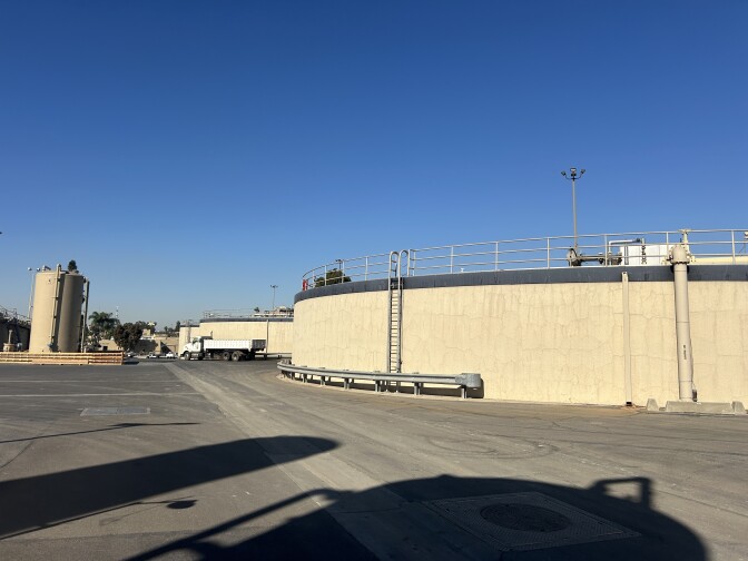 Large tan circular structures in a cement driving/parking area under sunny blue skies. 