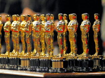 many gold statues of bald men lined up on a podium