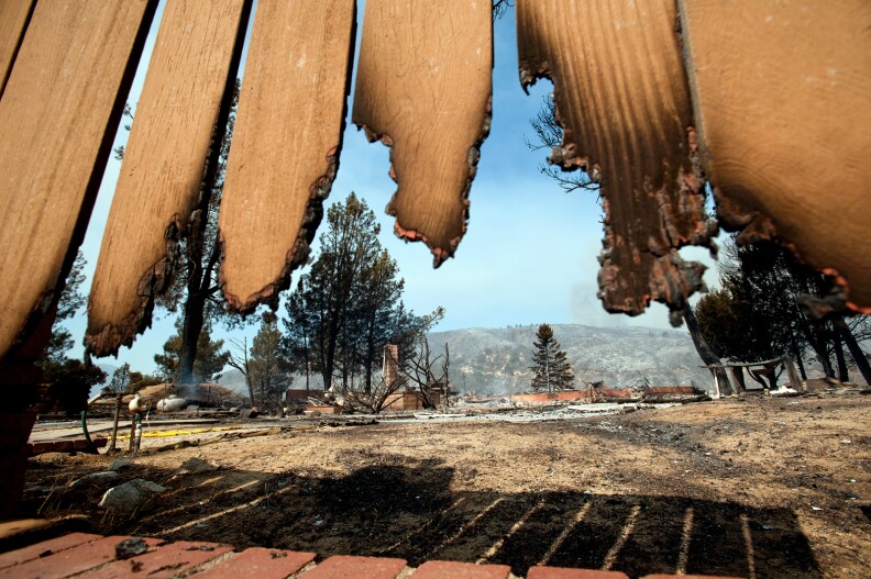 A burned-down home on Newview Road in Lake Hughes, seen through a burned fence.