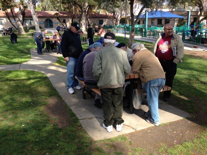 Russian speakers crowd around a picnic table in West Hollywood's Plummer Park.