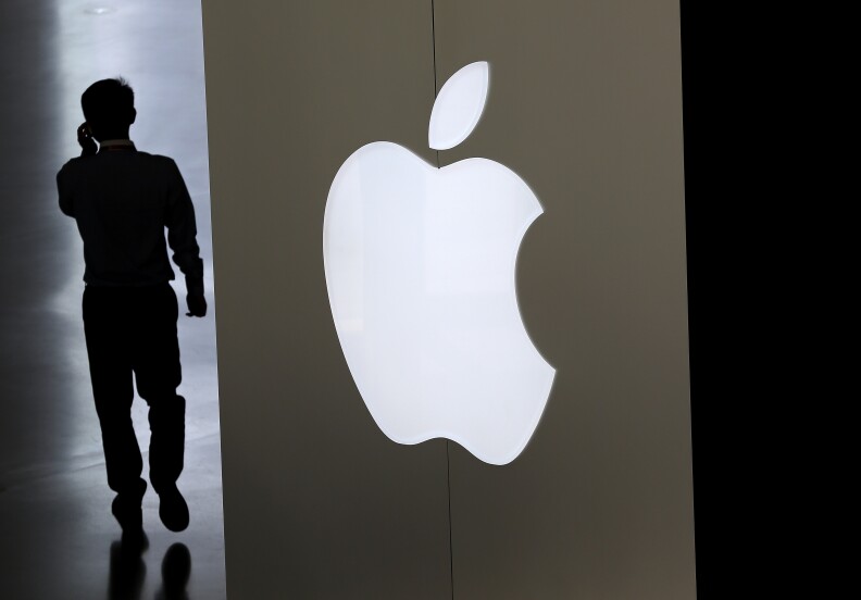 A Chinese man talking on his smartphone walks into an Apple store in Beijing Friday, Sept. 5, 2014. An Apple supplier in China is violating safety and pay rules despite the computer giant’s promises to improve conditions, two activist groups said Thursday ahead of the release of the iPhone 6. (AP Photo/Andy Wong)