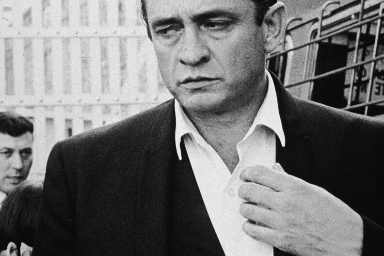 American country singer and songwriter Johnny Cash (1932 - 2003) walks inside the gates of Folsom Prison, preparing to perform his fourth concert for inmates there, California, 1964.