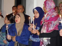 Mita Tommy of Reseda, in the blue coat and brown headscarf, joins in a candlelight vigil at the Islamic Center of Los Angeles for victims of the Paris terrorist attacks