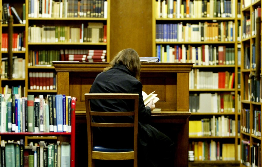 A student studies at a desk surrounded by books in the main library at the University College London on December 1, 2003 in London.